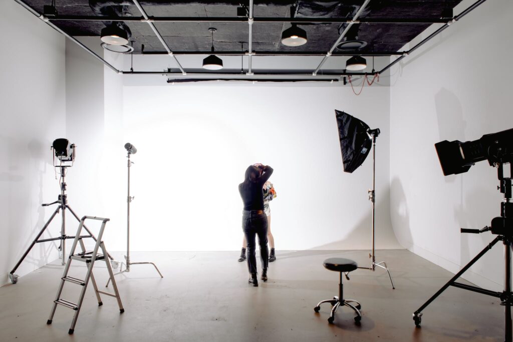 Back view of unrecognizable professional photographer taking photo of anonymous model in modern light studio